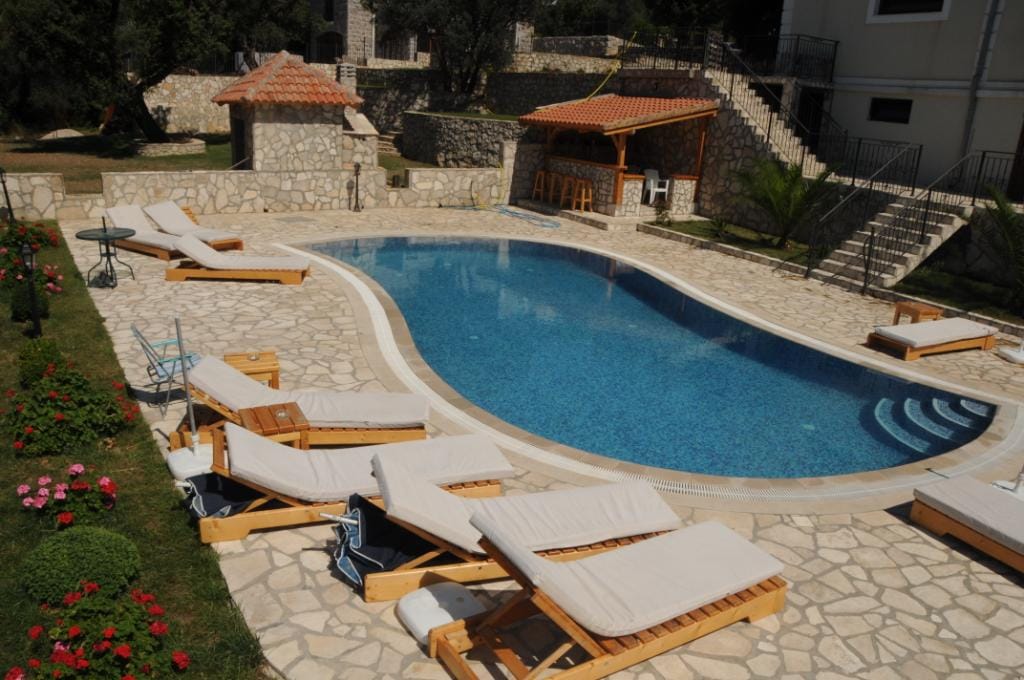 Outdoor pool with sun loungers and barbecue area on the villa grounds in Markovići, Montenegro.