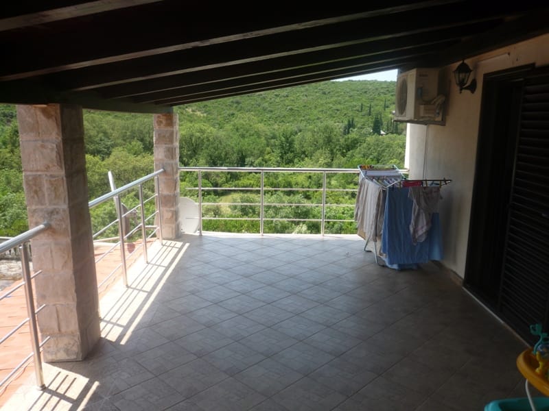 Spacious terrace with stone columns and views of green hills in a villa in Bigovo, Montenegro.