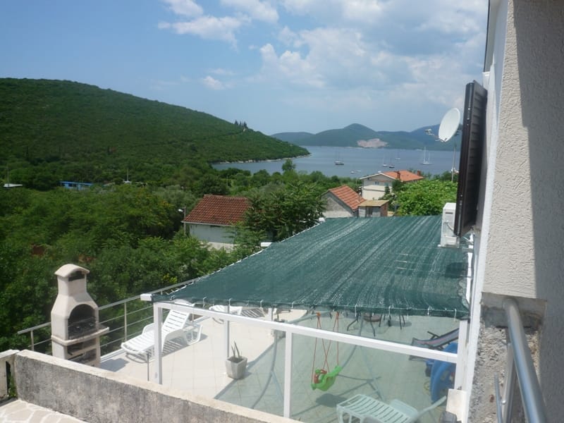 Villa terrace in Bigovo, Montenegro: sea view, sun loungers, garden swing, and a stone barbecue on the balcony.