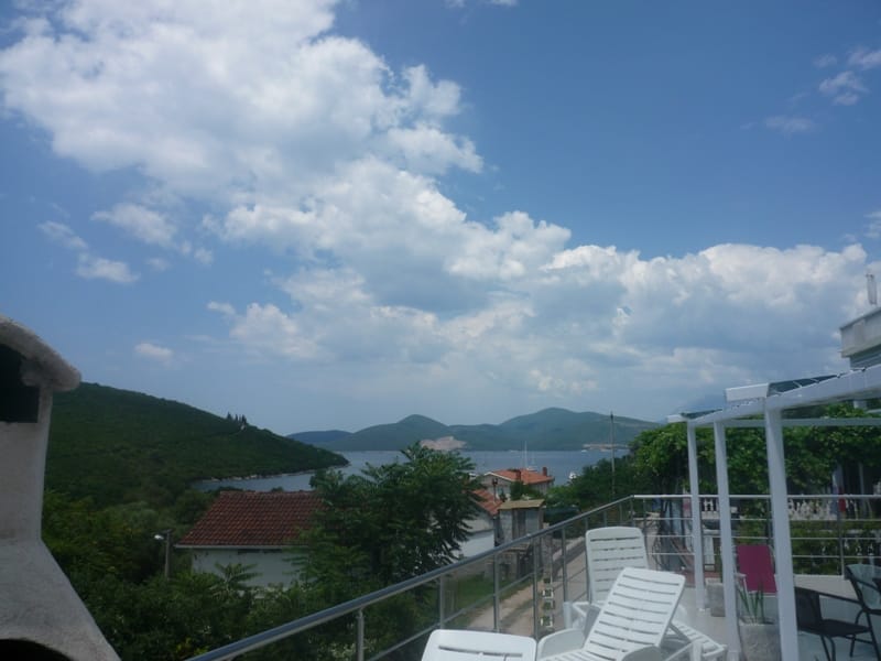 View from the villa terrace in Bigovo, Montenegro: white sun loungers, panoramic sea view, mountains, and Mediterranean landscape.