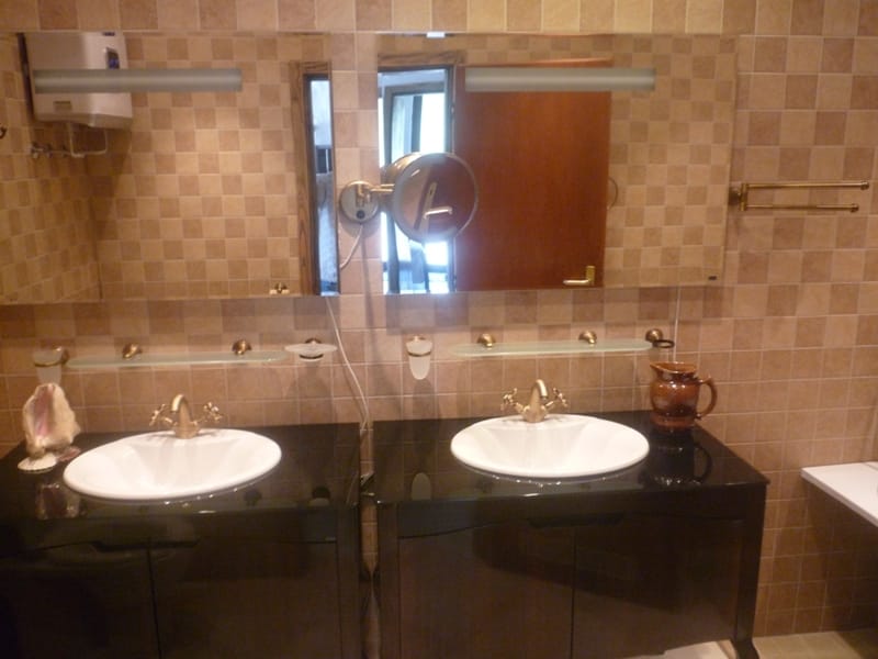 Bathroom with two sinks and a black vanity in a villa in Bigovo, Montenegro. Finished with beige tiles.