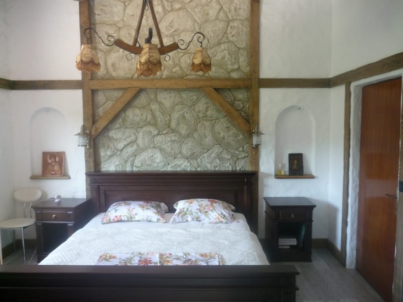 Bedroom in a villa in Bigovo, Montenegro: double bed, stone and wood finishes, wall niches, stylish interior.