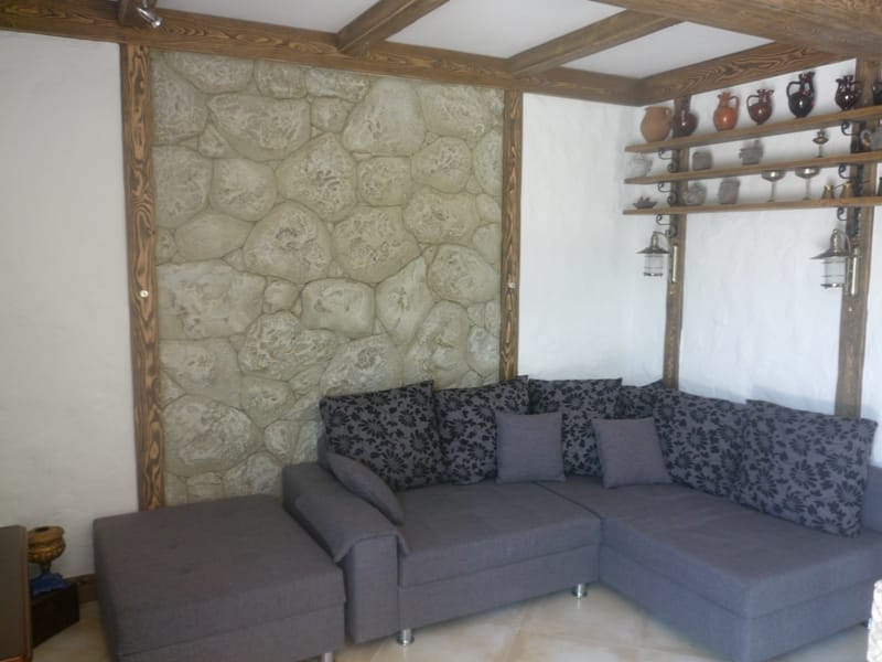 Living room in a villa in Bigovo, Montenegro: corner sofa, natural stone wall finish, and wooden beams.
