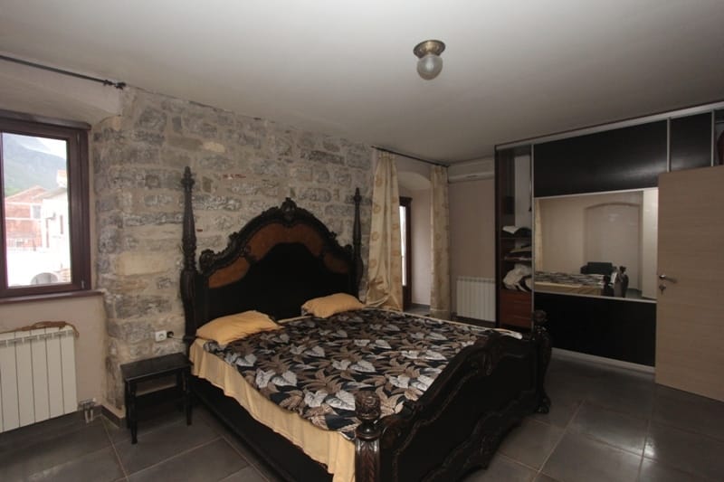 Bedroom in a villa in Prčanj, Montenegro: a solid bed, natural stone finishes, and a built-in wardrobe.