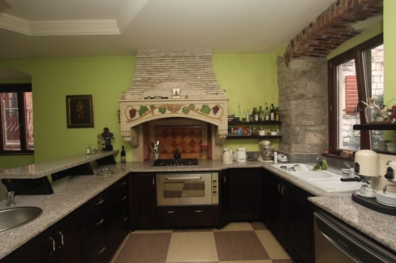 Kitchen in a villa in Prčanj, Montenegro: stone finishes, a decorative hood over the stove, granite countertops, and cabinetry.