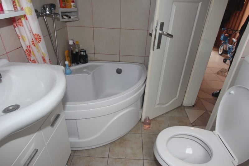 Bathroom with a corner bathtub and light-colored tiles in a house for sale in Muo, Montenegro.