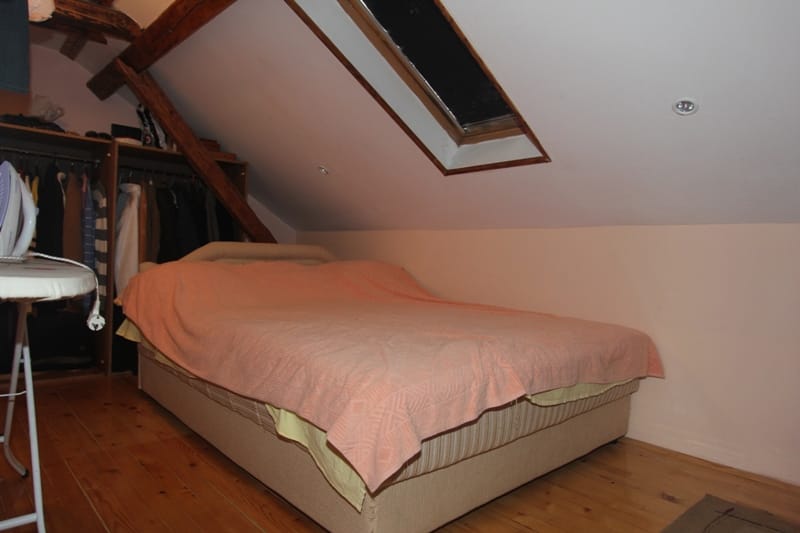 Cozy attic bedroom in a house in Muo, Montenegro: double bed, wooden beams, and a skylight.