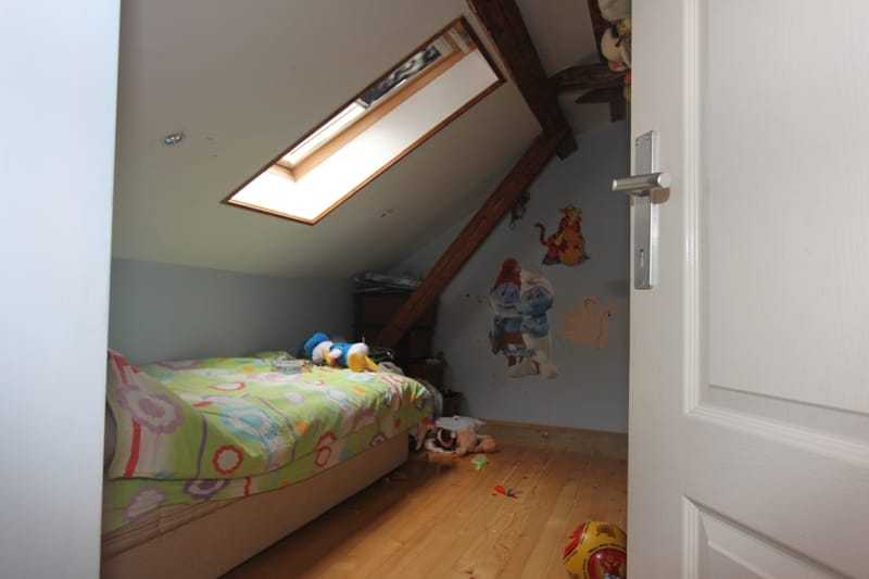 Children's bedroom in the attic with a slanted window and wooden beams in a house in Muo, Montenegro.