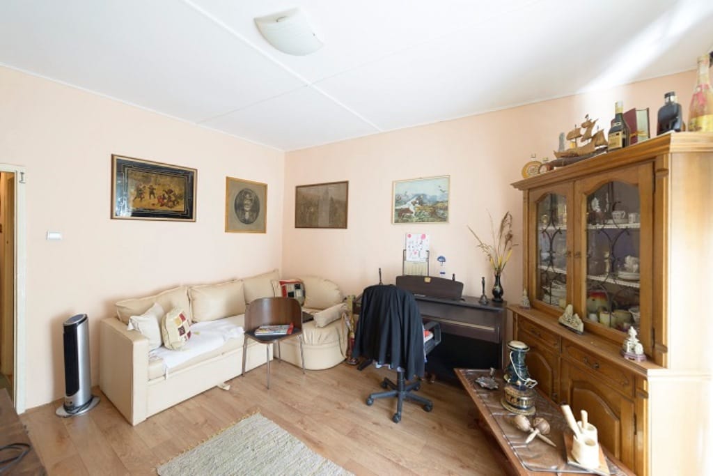 Living room in a house in Muo, Montenegro: bright interior with a beige sofa, wooden sideboard, and piano.