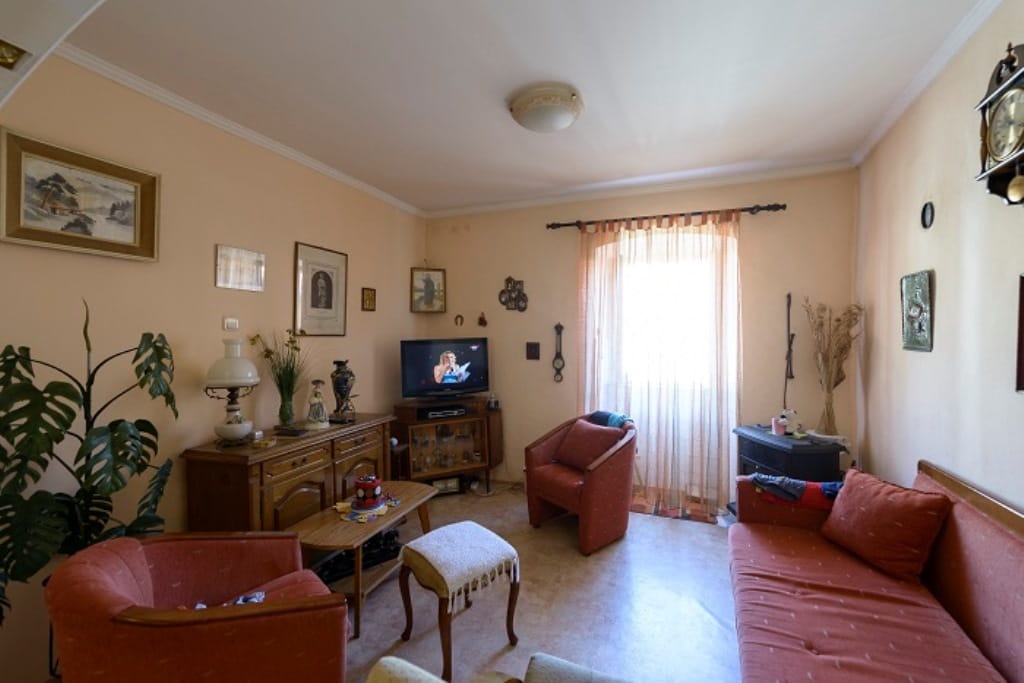 Cozy living room with classic furniture in a house for sale in Muo, Montenegro: a sofa set, TV, and decor.