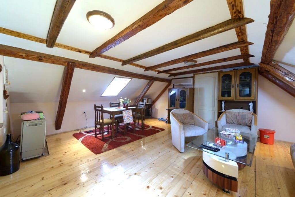 Living room in the attic of a house in Muo, Montenegro: wooden ceiling beams, parquet flooring, and a dining area.