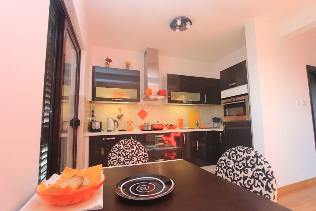 Modern kitchen with dark cabinetry and a dining area in an apartment in Rafailovići, Montenegro.