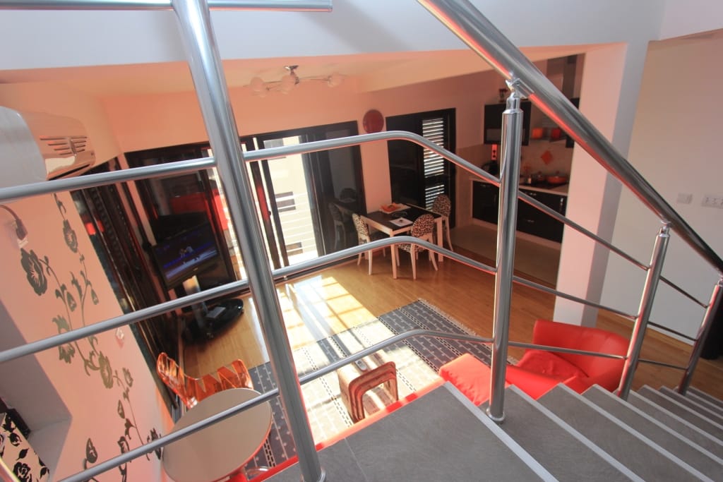 View from the staircase of the living room with a red armchair and kitchen in an apartment in Rafailovici, Montenegro. Modern interior.