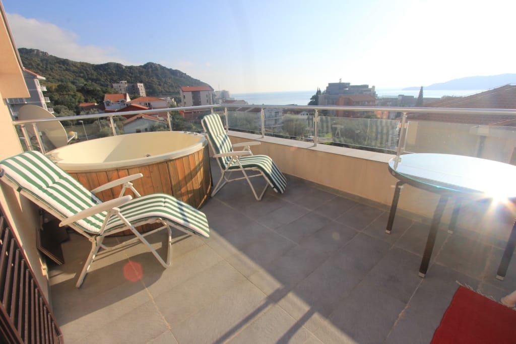 Apartment terrace in Rafailovici, Montenegro: jacuzzi, sun loungers, and panoramic sea and mountain views.