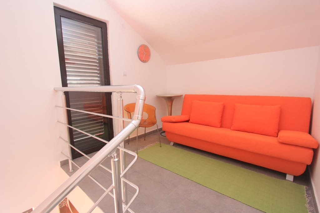 Living room with an orange sofa in an apartment in Rafailovici, Montenegro: modern interior and access to the balcony.