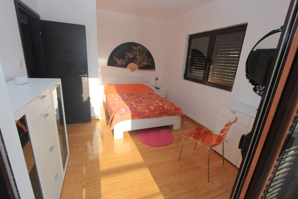 Bright bedroom in an apartment in Rafailovici, Montenegro: double bed, white furniture, parquet flooring, and Eastern-style decor