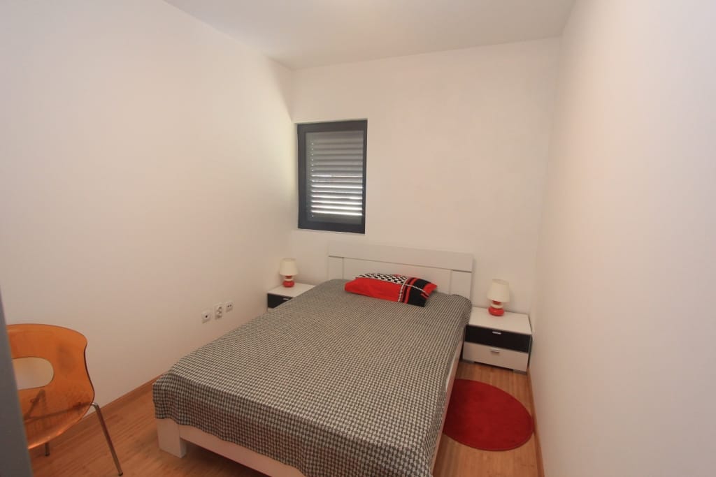 Bright bedroom with a double bed in an apartment, Rafailovići, Montenegro: modern furniture and a window with blinds.