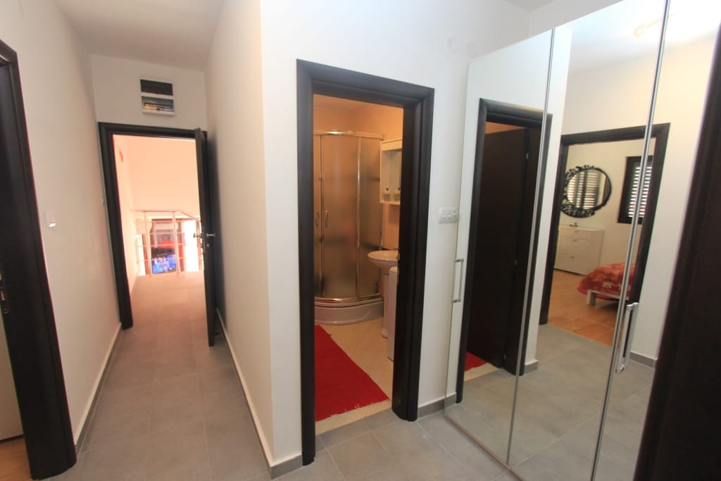 Hallway in an apartment in Rafailovici, Montenegro: built-in mirrored wardrobe, light finishes, and entrance to the bathroom.