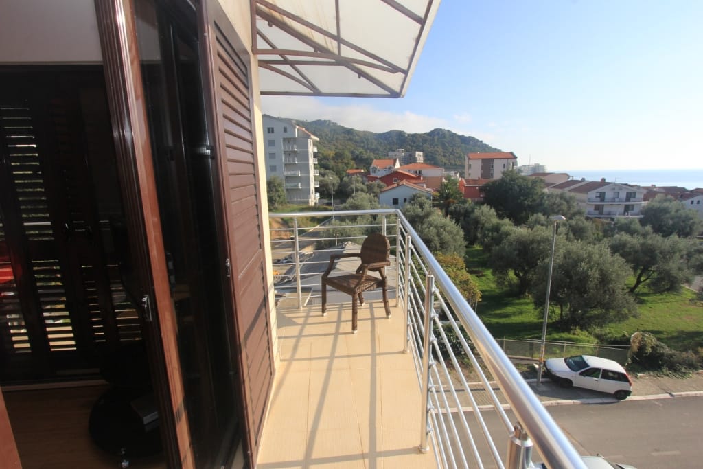 Balcony with wicker furniture and a view of the mountains and sea in an apartment in Rafailovići, Montenegro.