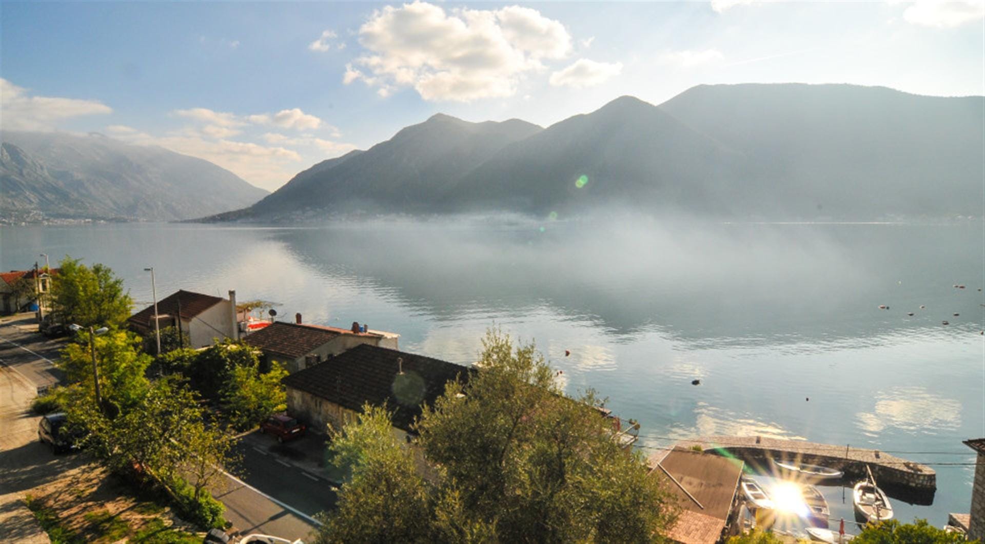 Panoramic view of the Bay of Kotor and mountains from a villa in Dražin Vrt, Montenegro: coastline and boat pier.