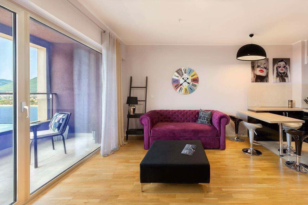 Living room with a purple sofa and panoramic sea view in an apartment, Becici, Montenegro.