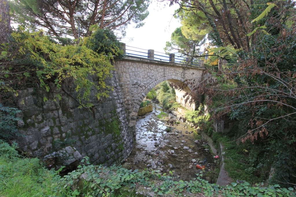 Picturesque stone bridge over a stream near a mini-hotel in Igalo, Montenegro: view of the surrounding area.