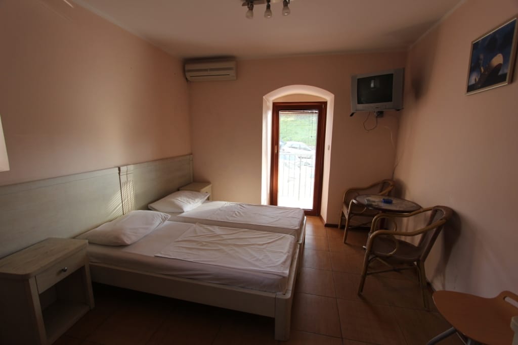 Bedroom in the Igalo mini-hotel, Montenegro: two beds, light-colored furniture, air conditioning, TV, and access to the terrace.