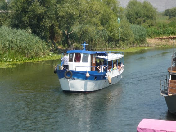 A sightseeing boat with tourists on the river in Virpazar, Lake Skadar, Montenegro, view of the restaurant business.