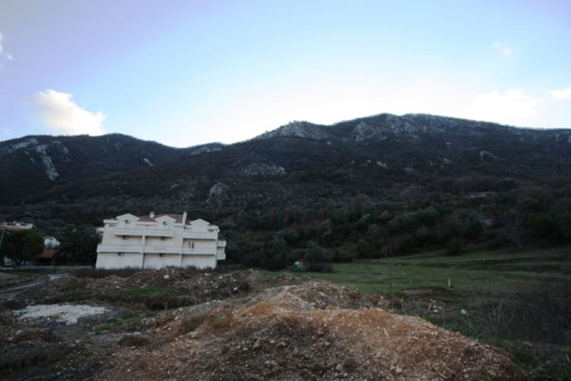 Land plot in Stoliv, Montenegro: view of a residential house and mountain scenery, a promising place for construction.