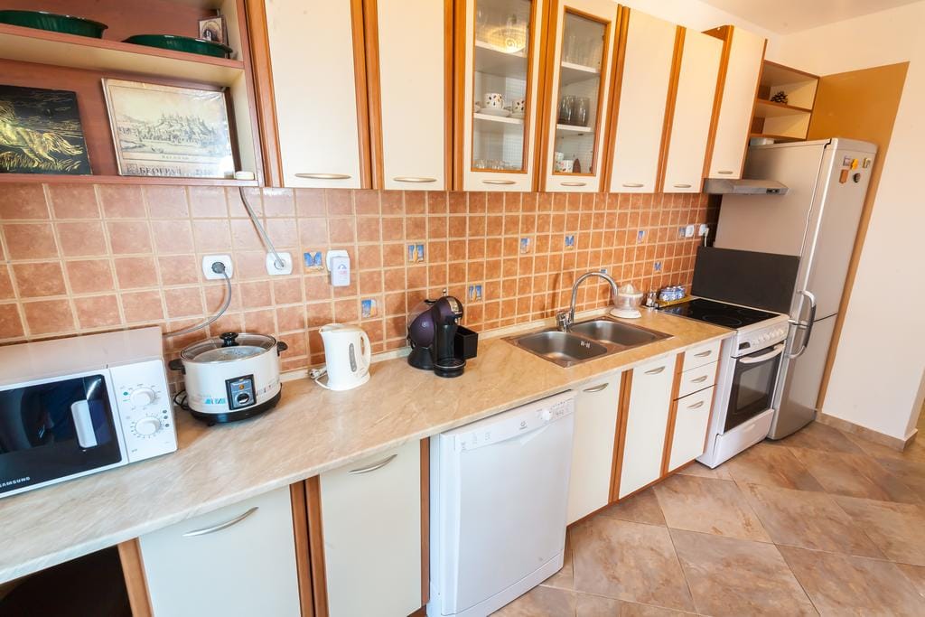 Cozy kitchen in a house in Krymovice, Montenegro: light-colored cabinets, built-in appliances, and tile backsplash.