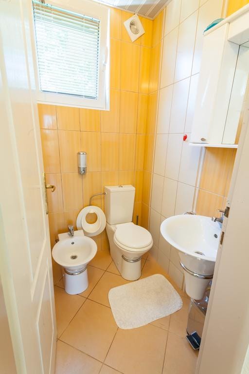 Bathroom with yellow tiles, plumbing fixtures, and a bidet in a house for sale in Krimovice, Montenegro.