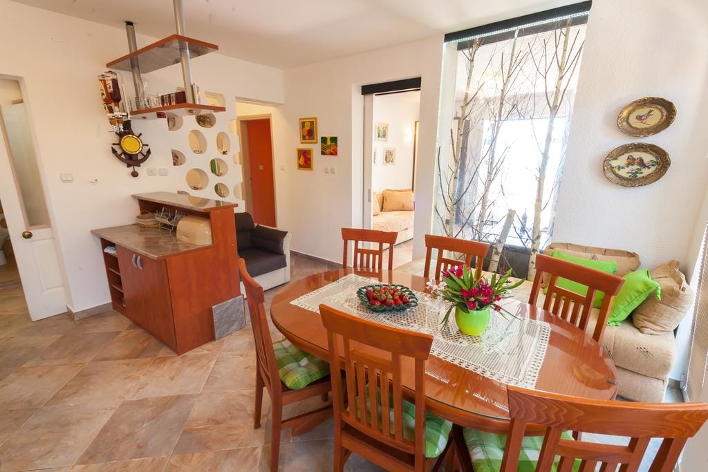 Living room with dining area and bar counter in a house in Krimovica, Montenegro: wooden furniture, decor, and panoramic windows.