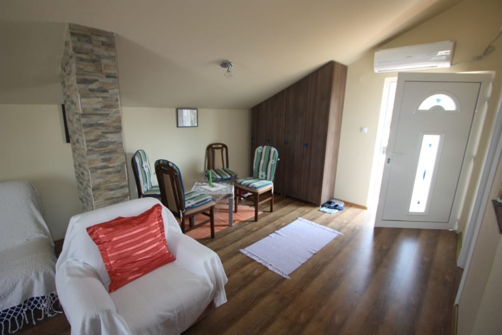 Living room in a house in Utjeha, Montenegro: attic floor, stone finish, wooden cabinet, armchairs, and access to the terrace.