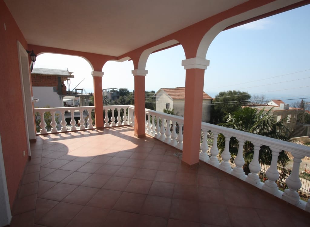 Spacious terrace with balustrade and sea view in a house, Uteha, Montenegro. Tiled floor, arched columns.
