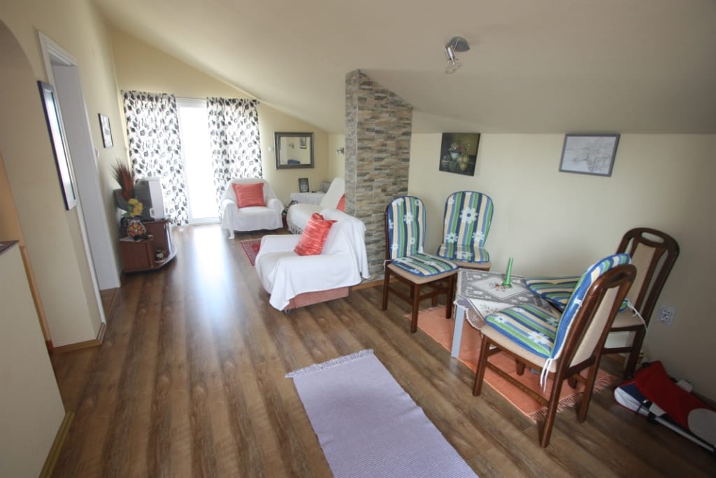 Cozy living room in a house in Utjeha, Montenegro: attic floor, light furniture, stone finishes, and dining area.