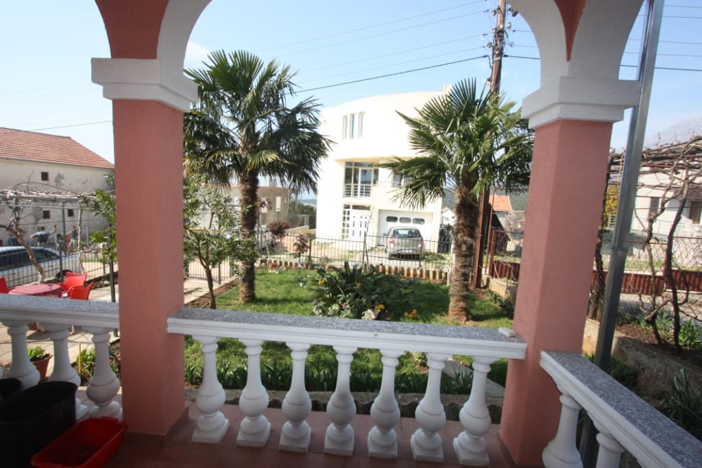 View from the terrace with a white balustrade of the green garden and palm trees by the house in Utjeha, Montenegro.