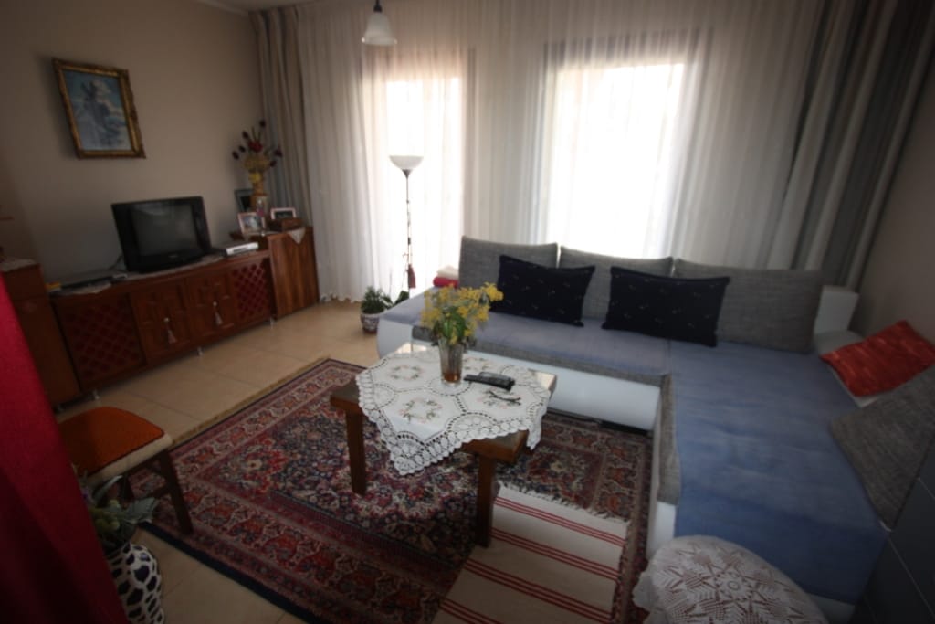 Cozy living room with an L-shaped sofa and rug in a house for sale in Utjeha, Montenegro: interior with furniture and TV.