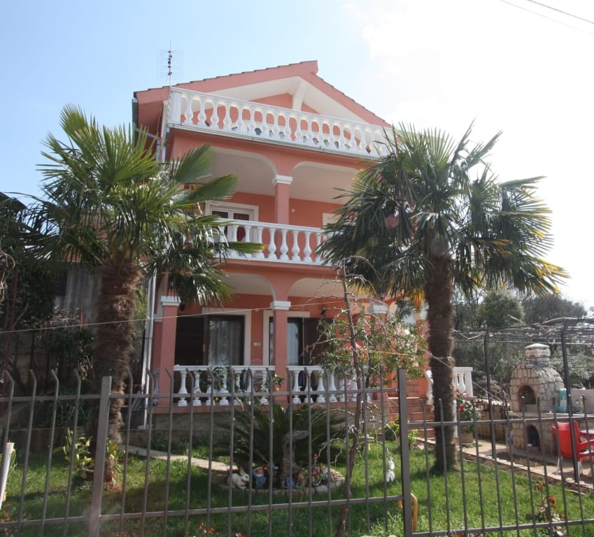Three-story pink house with terraces and palm trees in the garden, property for sale in Utjeha, Montenegro.