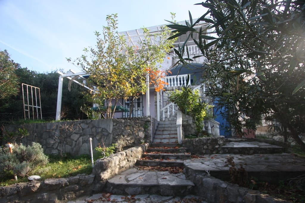 Two-story house in Uteha, Montenegro: stone staircase, terrace with pergola, and garden on the property.