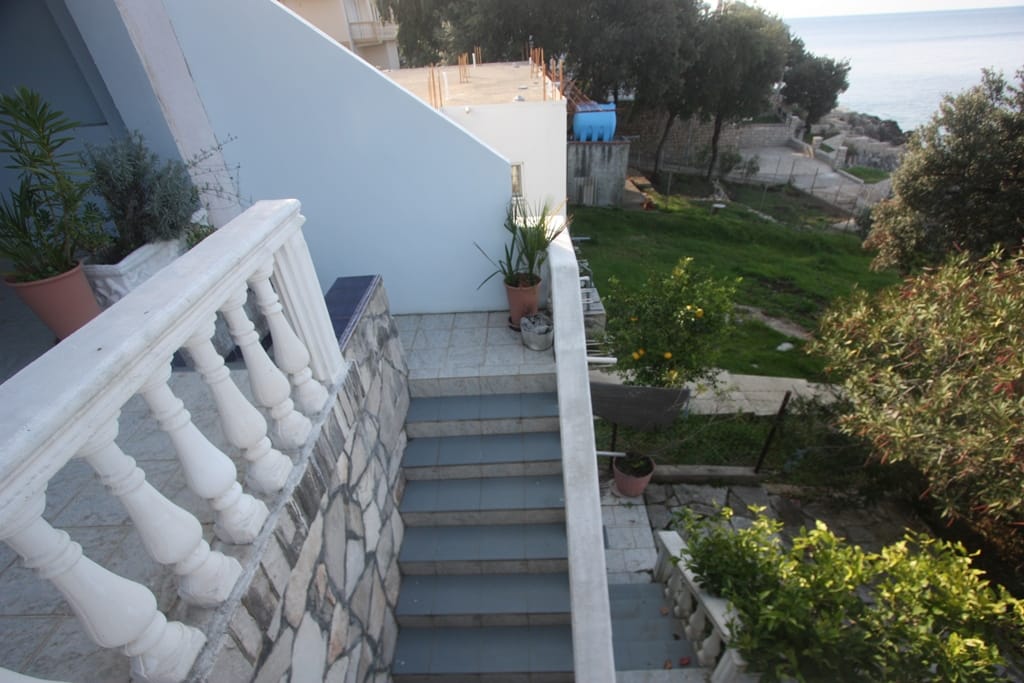 View from the balcony of a house in Utjeha, Montenegro: stone staircase, balustrade, and panoramic view of the sea and garden.