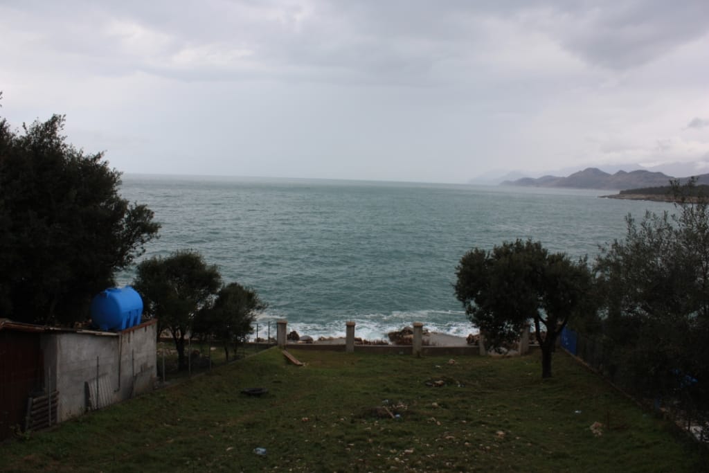 Sea view from the house plot in Utjeha, Montenegro: a green garden, fencing, and direct access to the Adriatic coast.