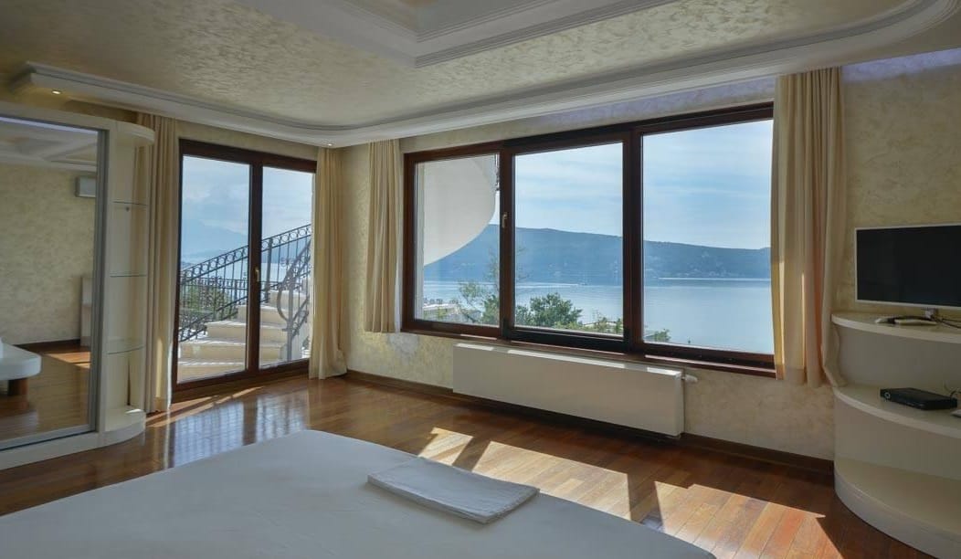 Bedroom in a villa in Herceg Novi, Montenegro: panoramic windows with sea views, parquet flooring, and access to the terrace.