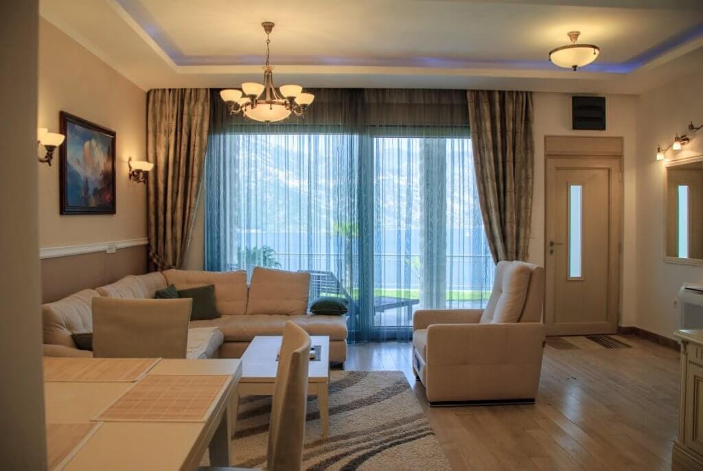 Cozy living room with soft furniture and sea view in an apartment in Kostanica, Montenegro. Modern interior with a terrace.