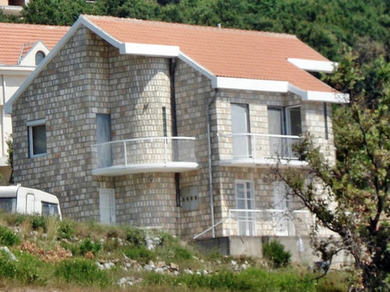 Two-story light stone house with terraces in Sveti Stefan, Montenegro: exterior view of a private villa.