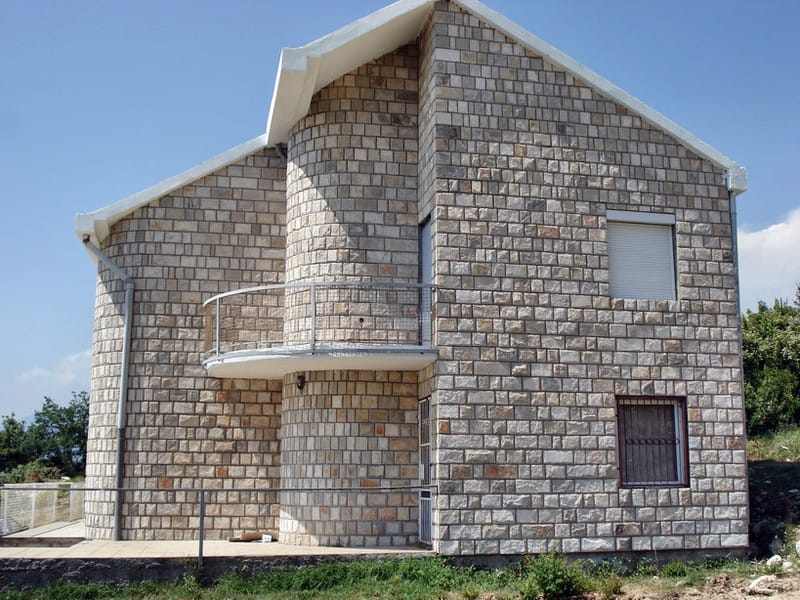 Two-story natural stone house with a semicircular balcony in Sveti Stefan, Montenegro. Building facade.