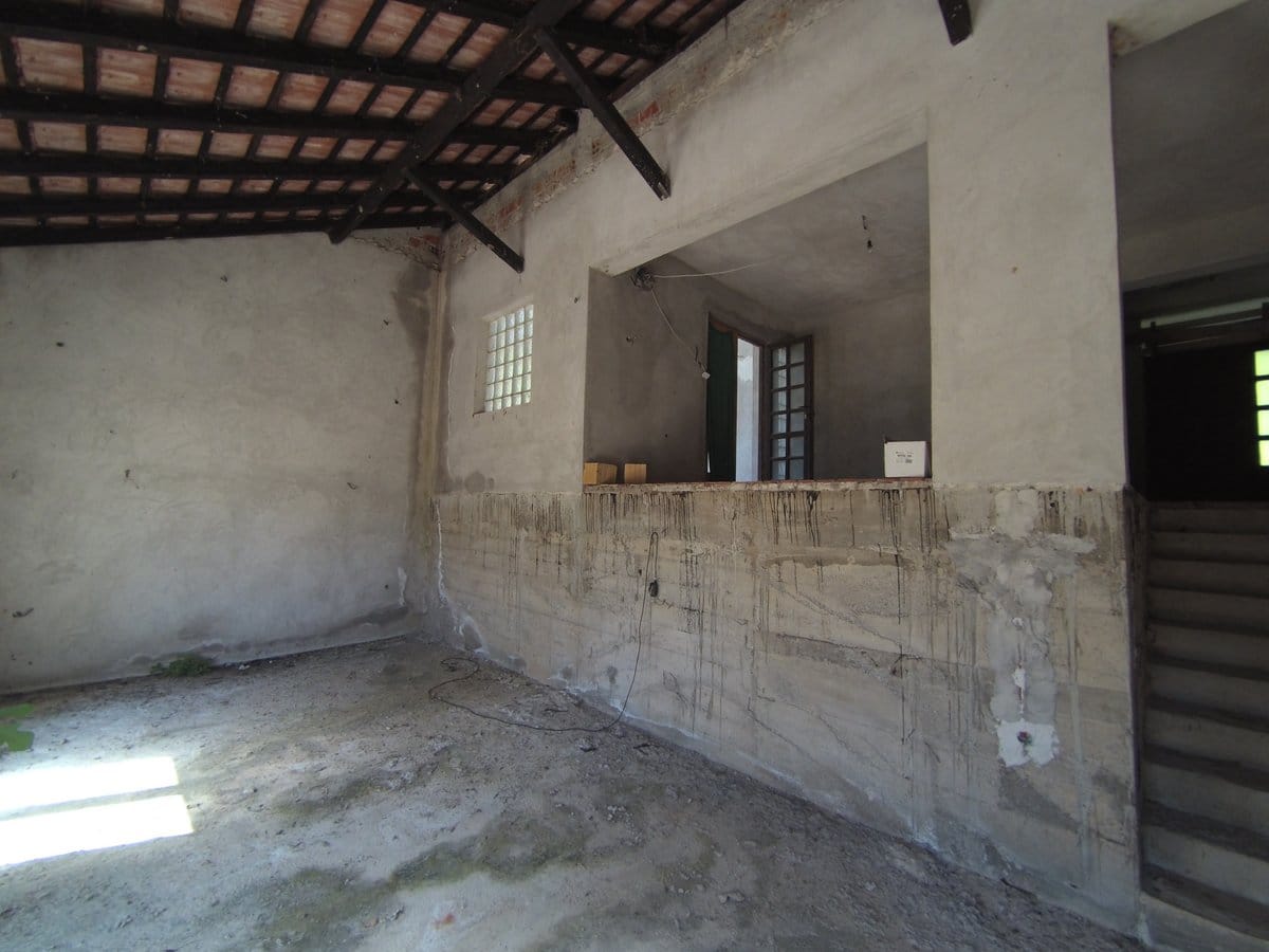 Renovation-ready space in a house in Kavac, Montenegro: concrete walls, exposed floor beams, and a staircase to the second floor.