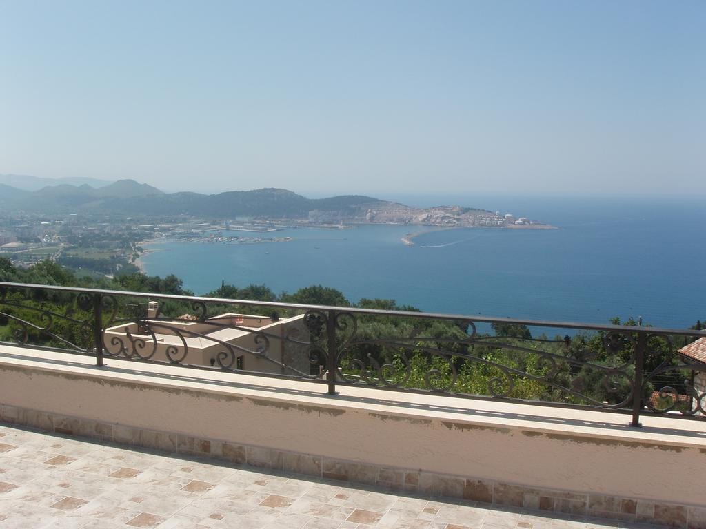 Panoramic view of the sea and bay from the terrace of a house in Šušanj, Bar Riviera, Montenegro, with wrought-iron railing.