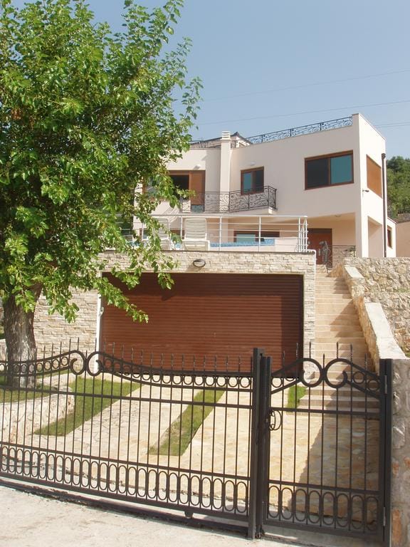Two-story villa in Šušanj, Bar Riviera, Montenegro: house with garage, terrace, and wrought-iron fence.