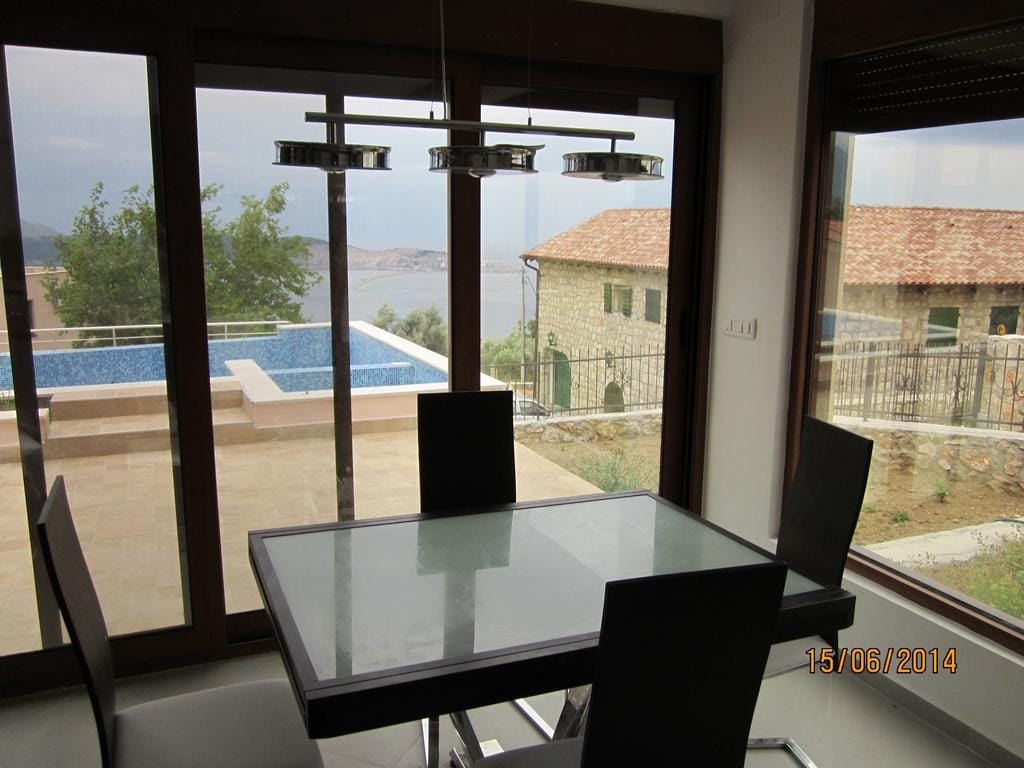 Living room with panoramic windows, dining table, and view of the pool and sea in a house, Bar Riviera, Montenegro.