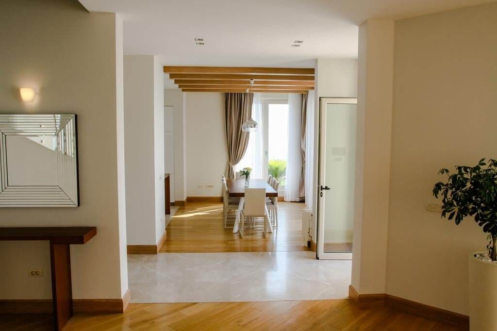 Bright living room with dining area and wooden beams in a villa in Blizikuće, Montenegro. Modern interior.